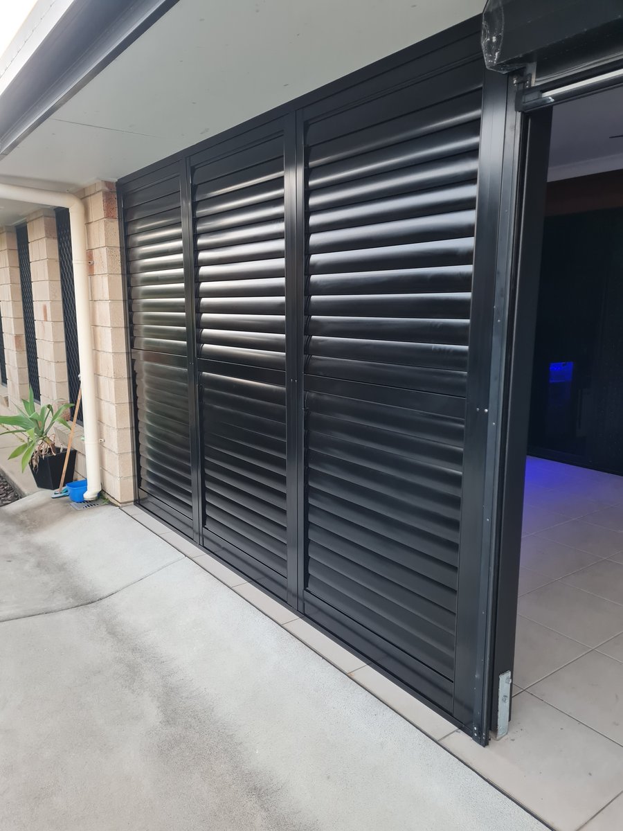 Black external aluminium sliding shutters on a patio