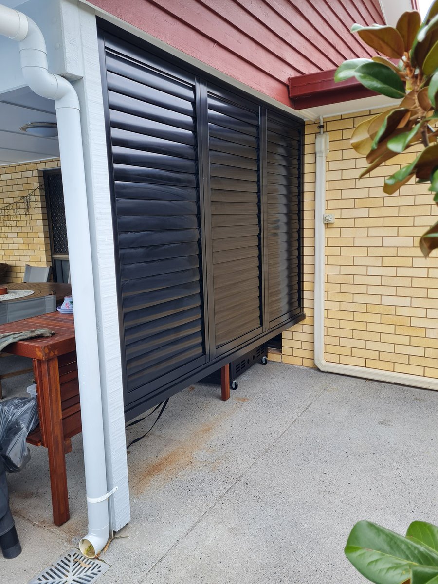 Black external aluminium shutters on a brick patio