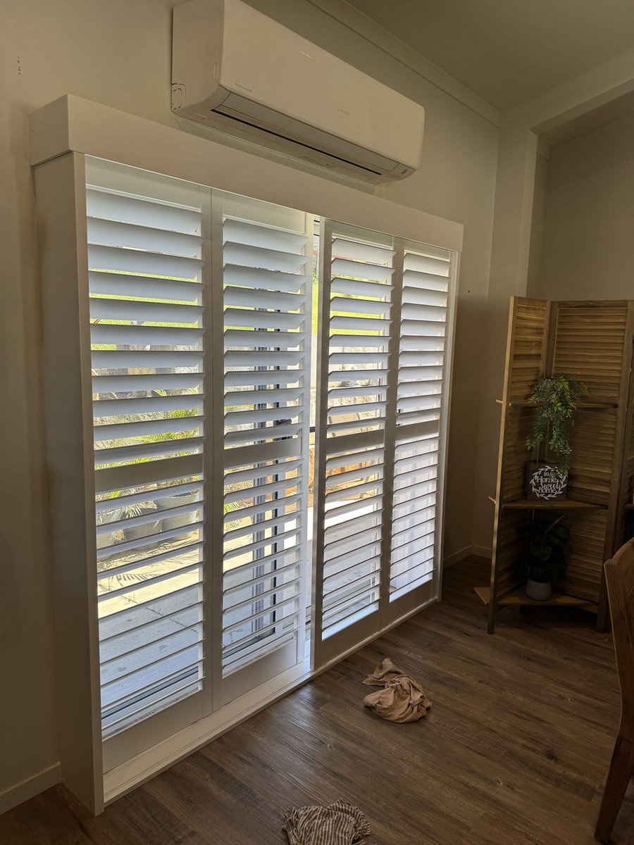 White plantation shutter panels over a sliding glass door